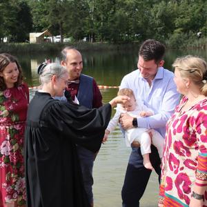 Taufe am Badesee Schortens: Pastorin tauft ein Baby, das auf dem Arm gehalten wird