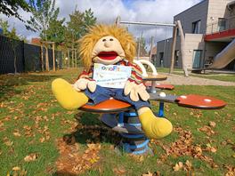 Eine große Handpuppe hält ein Schild, auf dem steht: PhonoFit - wir sind eine Sprachkita